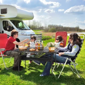 Familie beim Picknick vor Wohnmobil im Freien.